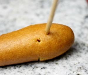 Use a dowel to make the bite marks in Vampire Bitten Corn Dogs