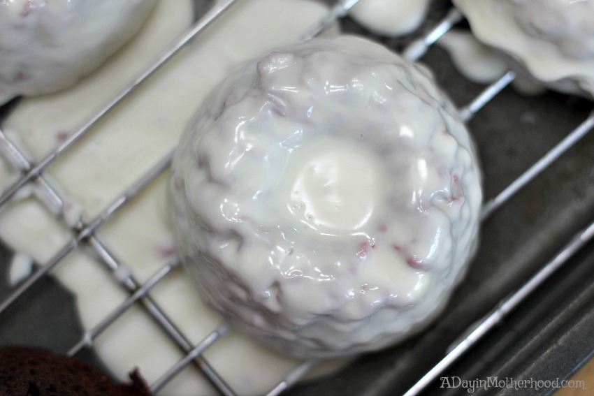 Pat the tray down on the table to smooth the coating over the Red Velvet Easter Cakes