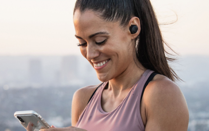 JLab Headphones: #1 True Wireless Headphones under $100 - photo of woman on her phone on adayinnmotherhood.com